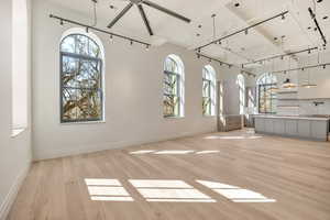 Unfurnished living room featuring track lighting and light wood-style flooring