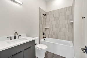 Bathroom with vanity, tub / shower combination, and dark tile patterned flooring