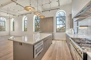 Kitchen featuring track lighting, modern cabinets, a large island, light wood finished floors, and light stone counters
