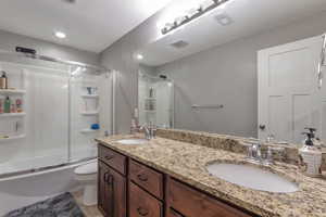 Full bath featuring double vanity and shower / bath combination with glass door
