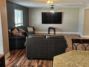 Living area featuring dark wood-type flooring and ceiling fan