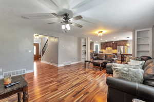 Living area featuring built in features, wood finished floors, and a ceiling fan
