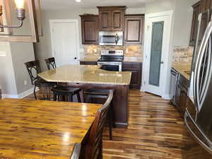 Kitchen featuring stainless steel appliances, a breakfast bar area, dark wood finish cabinetry, and dark wood finished floors
