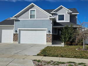 View of front of house featuring stone siding, driveway, an attached garage, and a garage