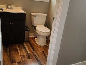 Half bathroom featuring vanity and dark wood finished floors
