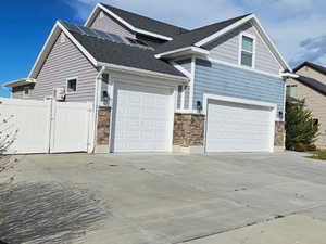 View of side of home with a residential view, concrete driveway, a gate, and an attached garage