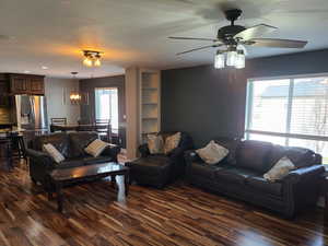 Living area with dark wood-type flooring, a ceiling fan, and recessed lighting
