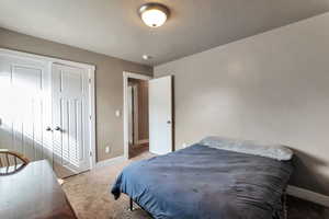 Bedroom with light colored carpet and a closet