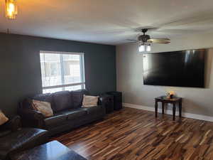 Living room featuring a ceiling fan and dark wood-type flooring