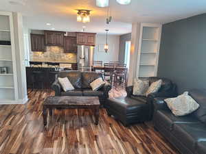 Living room featuring built in shelves and dark wood-style flooring