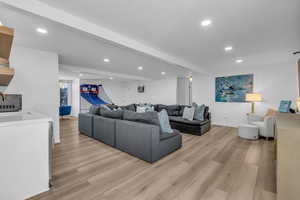 Living area with beamed ceiling, light wood finished floors, and recessed lighting
