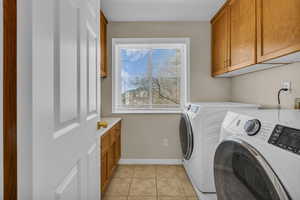 Laundry room featuring cabinet space, separate washer and dryer, and light tile patterned flooring