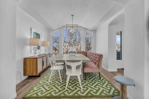 Dining room with light wood-style flooring, suspended lighting, healthy amount of natural light, and a barrel ceiling