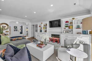 Living area featuring arched walkways, a fireplace, recessed lighting, and wood finished floors