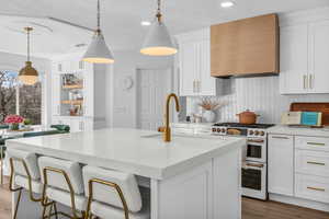 Kitchen with white cabinetry, a kitchen bar, high end stove, and a kitchen island with sink
