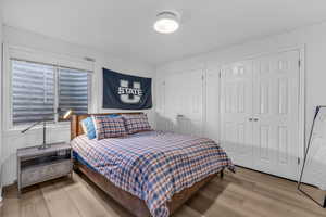 Bedroom with light wood finished floors and two closets