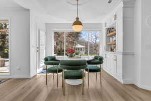 Dining space featuring light wood finished floors and crown molding