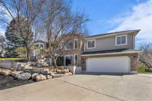View of front facade with an attached garage, concrete driveway, roof with shingles, and brick siding