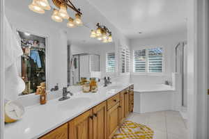 Full bath with a stall shower, double vanity, light tile patterned flooring, a bath, and a spacious closet