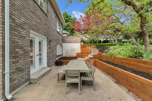 Expansive concrete patio area with multi-level terraced landscaping, featuring natural wood retaining walls and steps