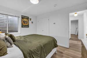Bedroom with light wood finished floors, a closet, and beamed ceiling