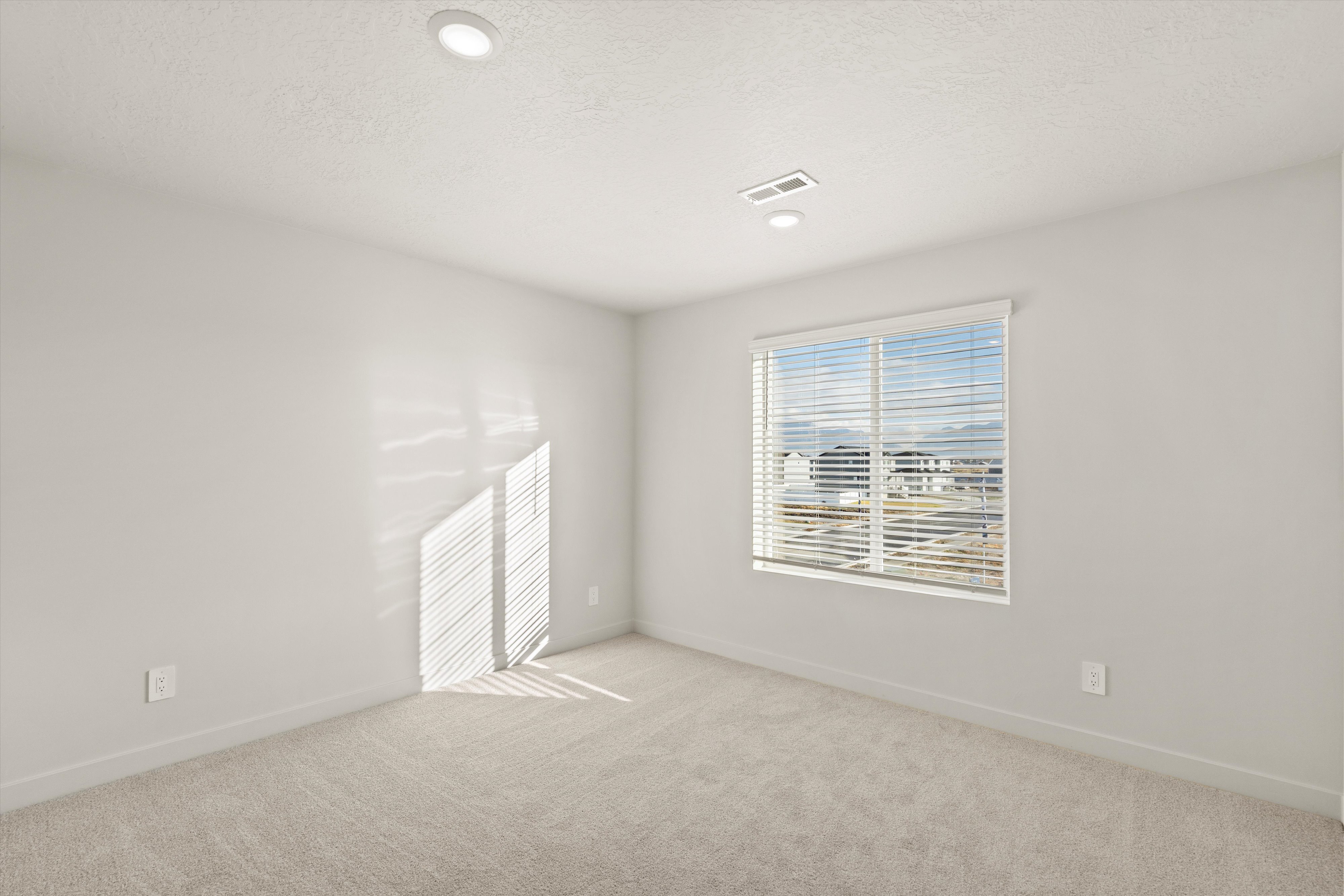 Empty room with light carpet, recessed lighting, and a textured ceiling