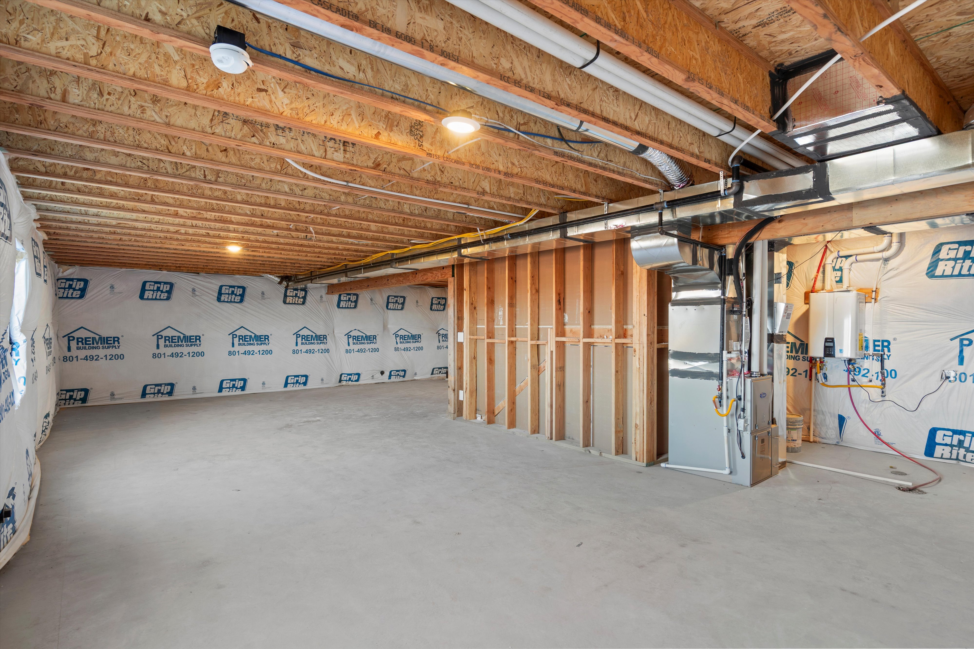 Unfinished below grade area featuring tankless water heater and heating unit