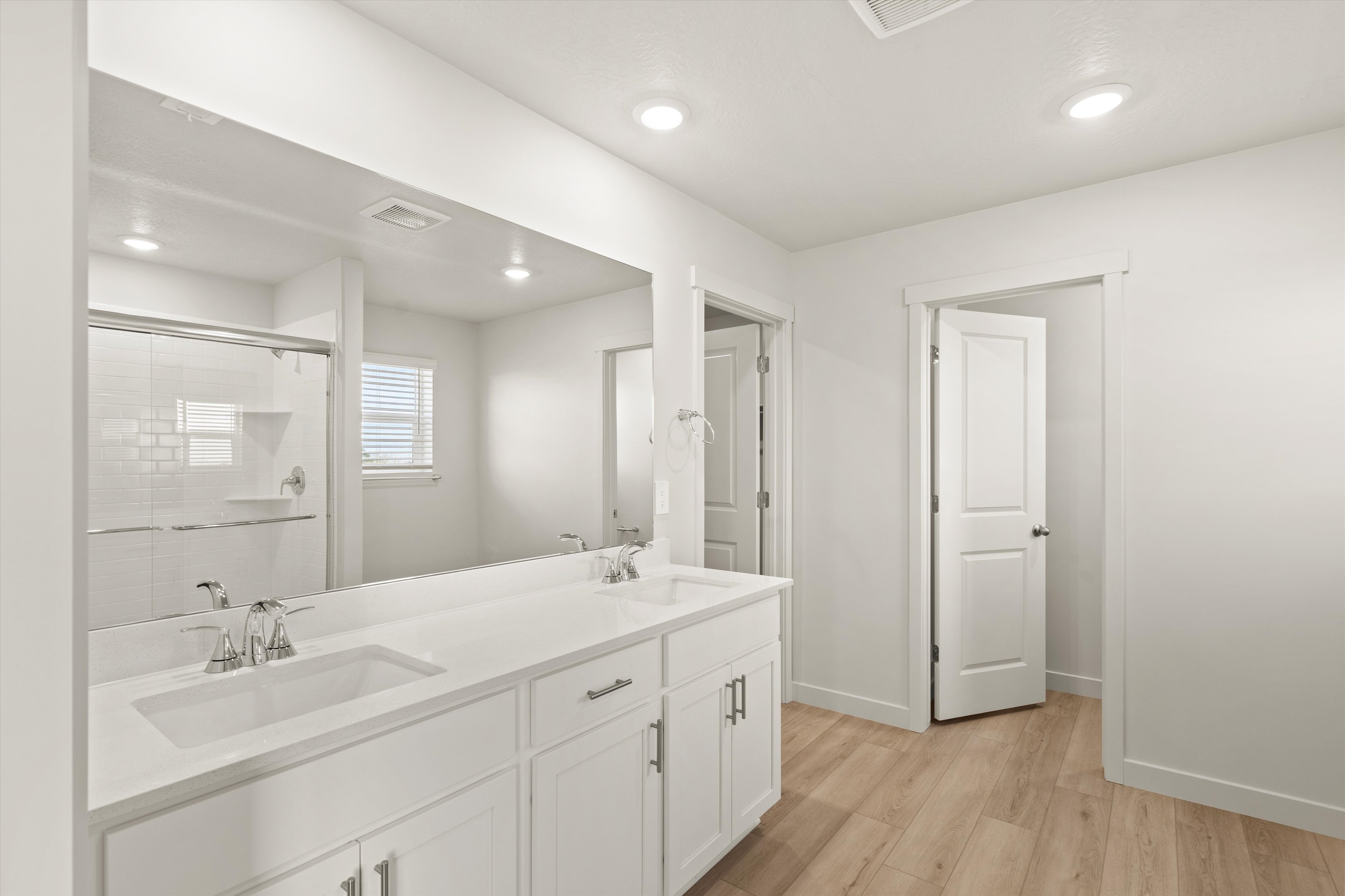 Full bath featuring double vanity, light wood-style floors, a shower stall, and recessed lighting
