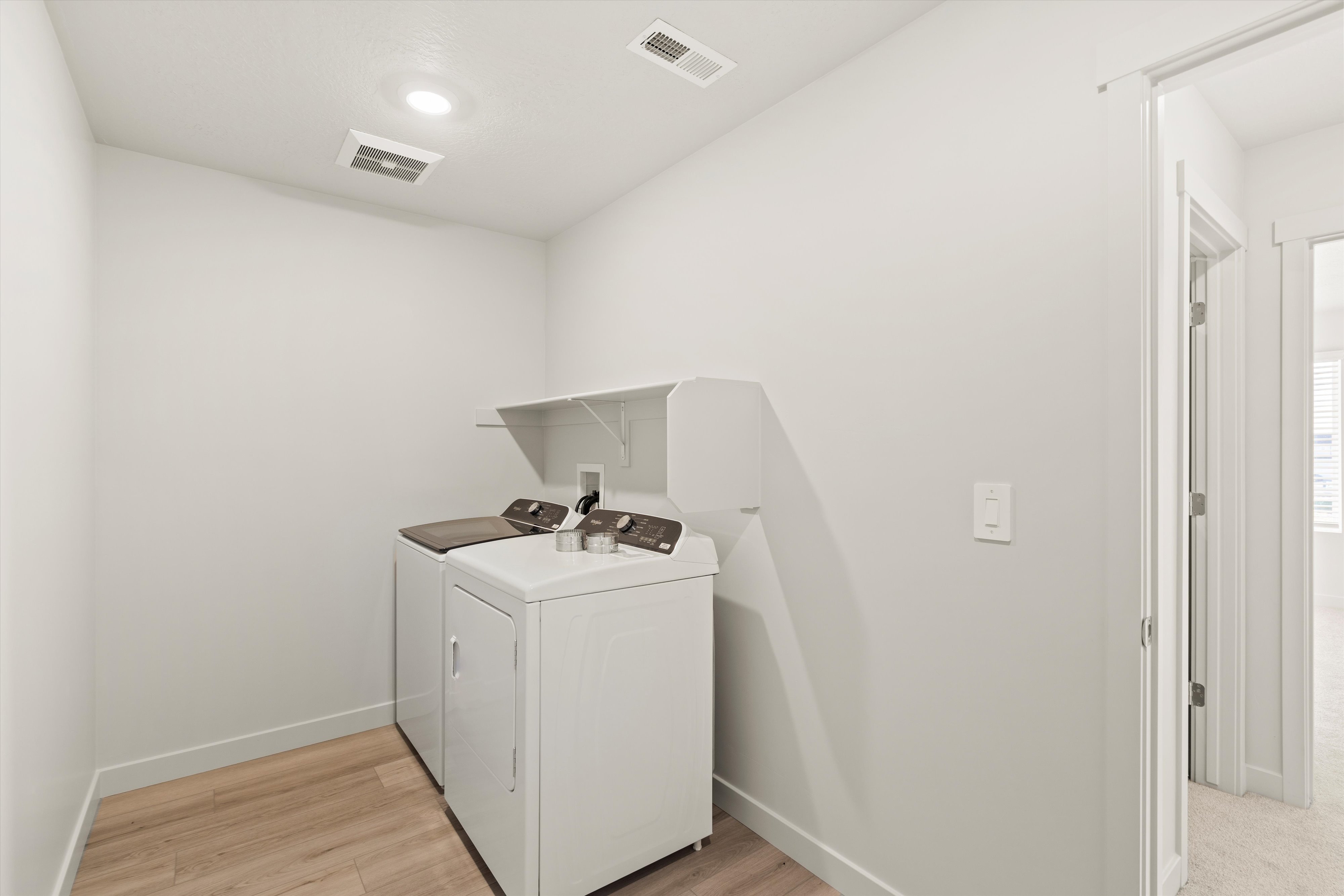 Laundry room with light wood-style flooring and washer and clothes dryer
