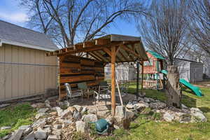 View of patio with a playground and a shed