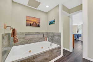 Bathroom featuring a tub with jets, ensuite bathroom, and dark wood finished floors