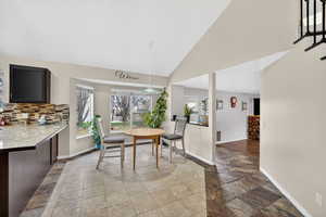 Dining room with vaulted ceiling and stone tile floors