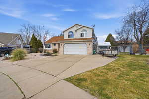 Traditional-style house with a gate, driveway, brick siding, and an attached garage
