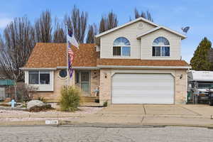 Traditional home with driveway, roof with shingles, an attached garage, and brick siding