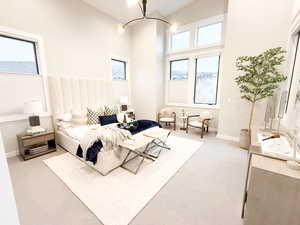 Bedroom featuring a high ceiling, light carpet, and suspended lighting