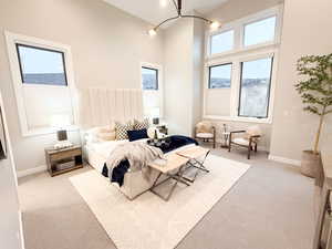 Bedroom featuring a high ceiling, a chandelier, and light carpet