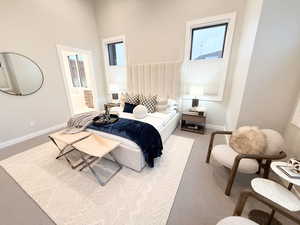 Carpeted bedroom featuring ensuite bath and a high ceiling