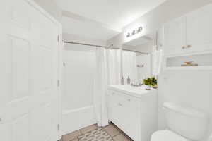 Full bath featuring vanity, shower / tub combo with curtain, and light tile patterned floors