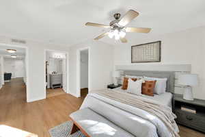 Bedroom featuring a spacious closet, light wood-type flooring, ceiling fan, and connected bathroom