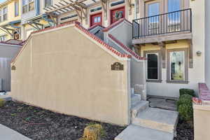View of exterior entry featuring stucco siding and stone patio