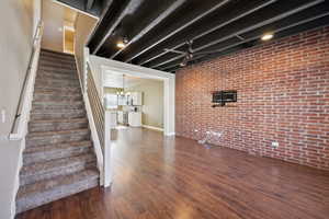 Staircase featuring brick wall, laminate flooring, and modern fan