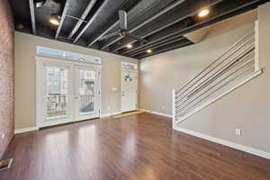 Foyer featuring brick wall, a ceiling fan, dark wood-style flooring, and french doors to small deck