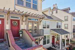 Entrance to property featuring stucco siding, roof with shingles, and a pergola