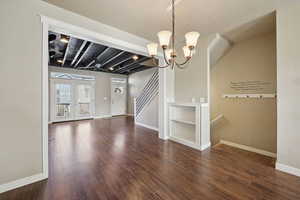Unfurnished dining area with built in shelves, dark wood-style flooring, and hanging lights