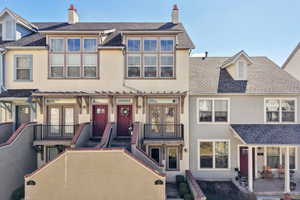 Front of house with stucco siding, a shingled roof. Small Deck and stone patio