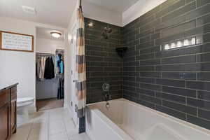 Primary suite features a walk-in closet and large soaking tub with tile surround