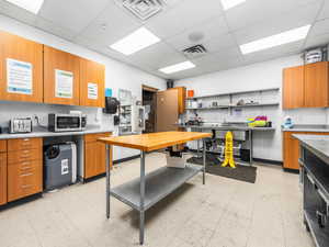 Kitchen featuring wood finish cabinets, a drop ceiling, and stainless steel microwave
