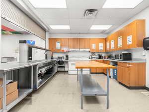 Kitchen with a paneled ceiling, white electric range, stainless steel microwave, stainless steel countertops, and dual tone cabinets