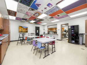 Dining area featuring light floors, concrete block wall, and a paneled ceiling