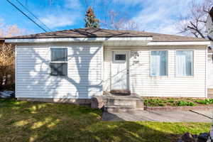 Back of house featuring a lawn and roof with shingles